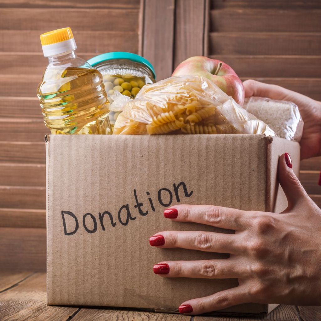 cardboard box full of food with the word donation printed on it held in someone's hand