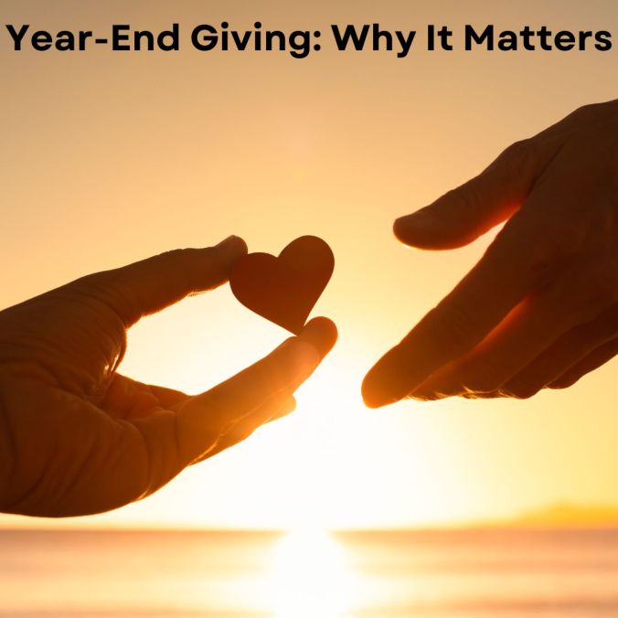 photo of one hand giving a heart to another heart in a sunset